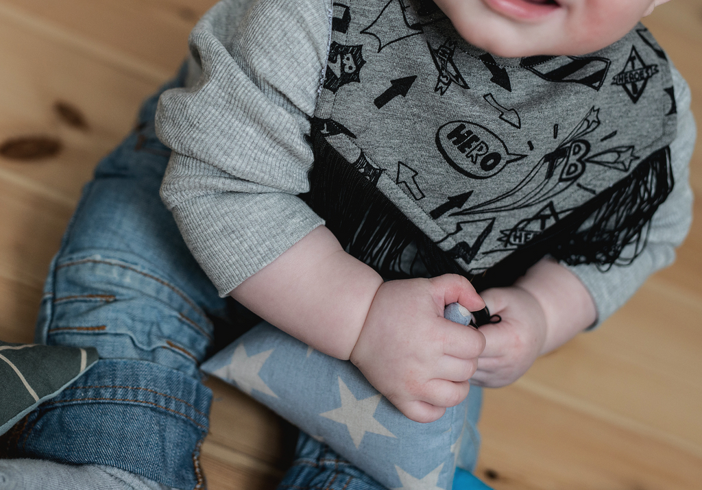 Toddler wearing grey and black drool bib 