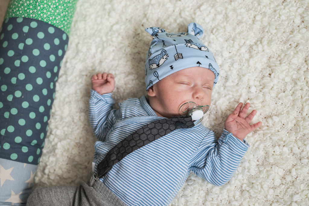 Newborn boy in blue beanie and binky leash